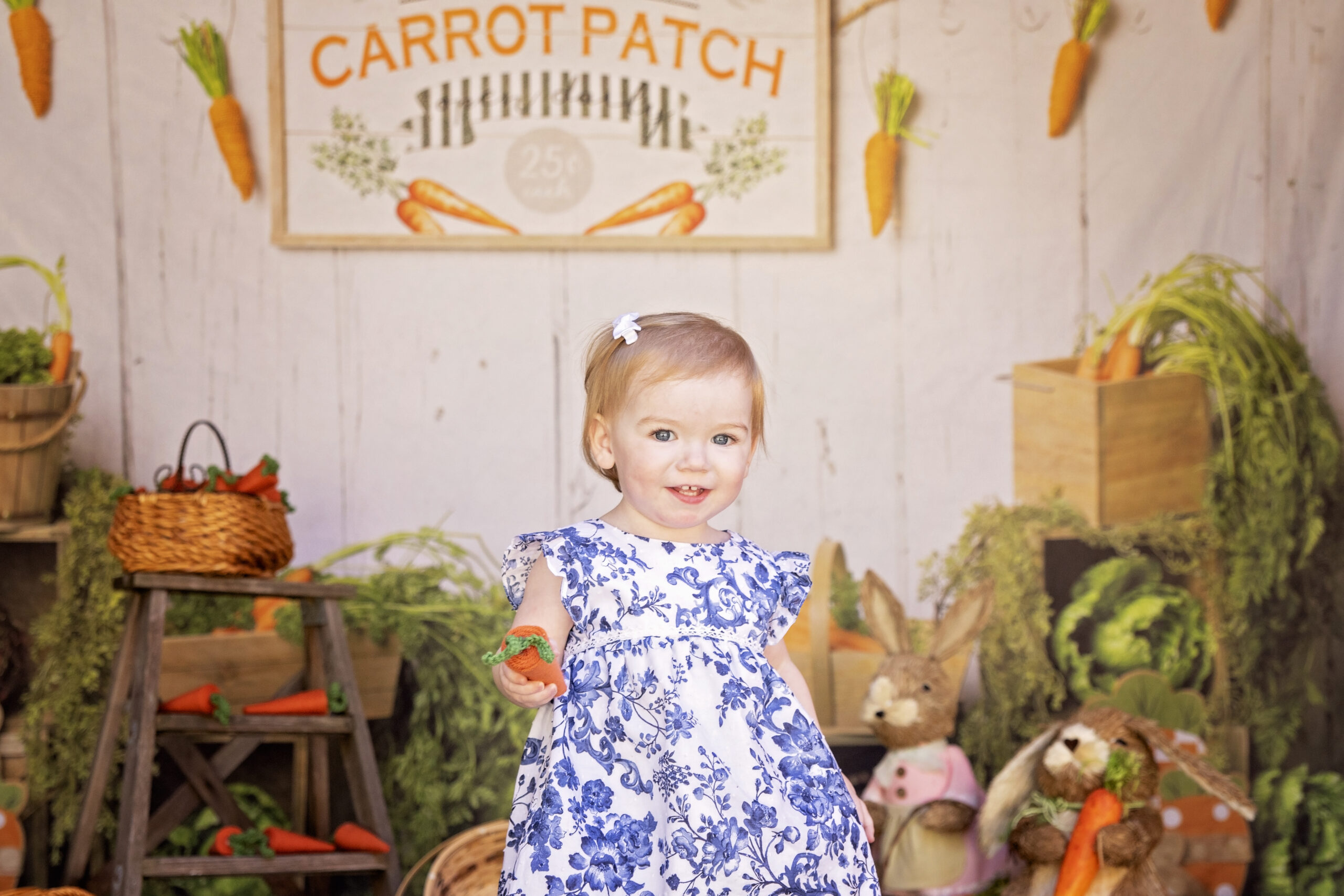 toddler smiling at the camera in a carrot patch