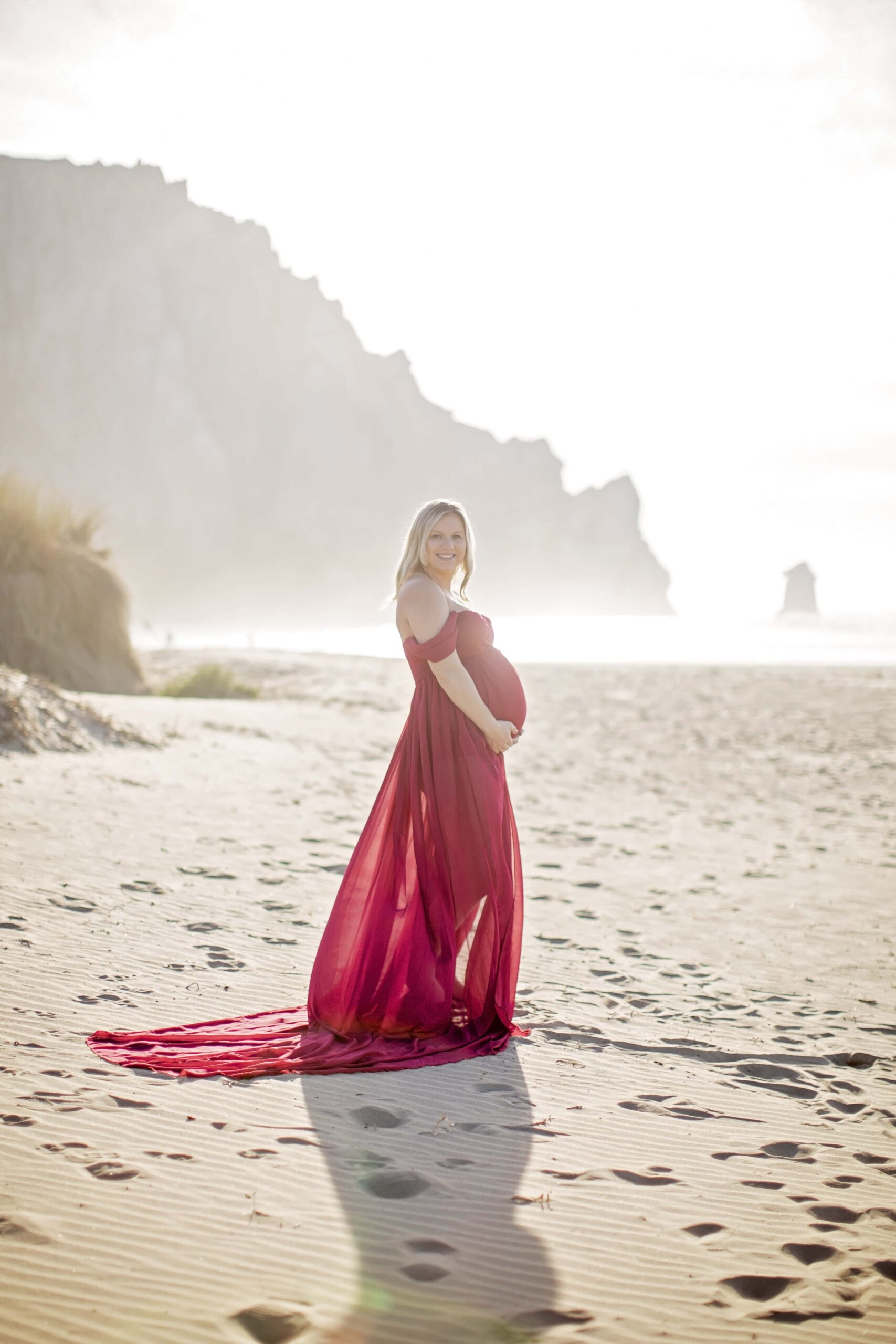 pregnant woman at the beach wearing a flowing red dress