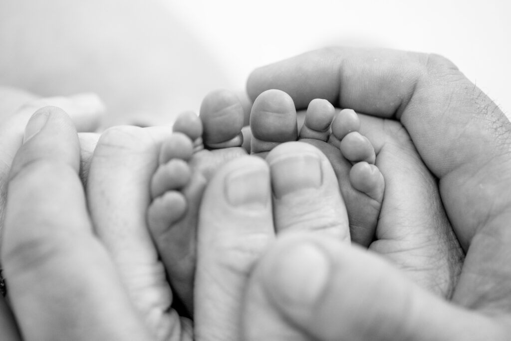 newborn feet with parent's hands around them