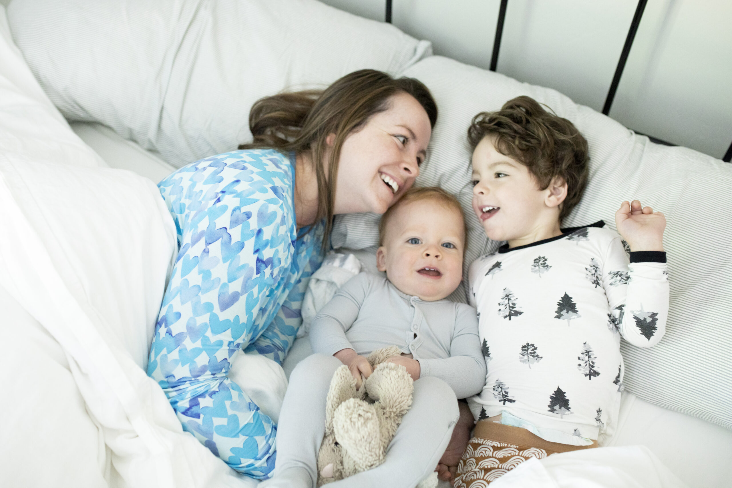 Mother and two young sons cuddling in bed during a lifestyle photo session