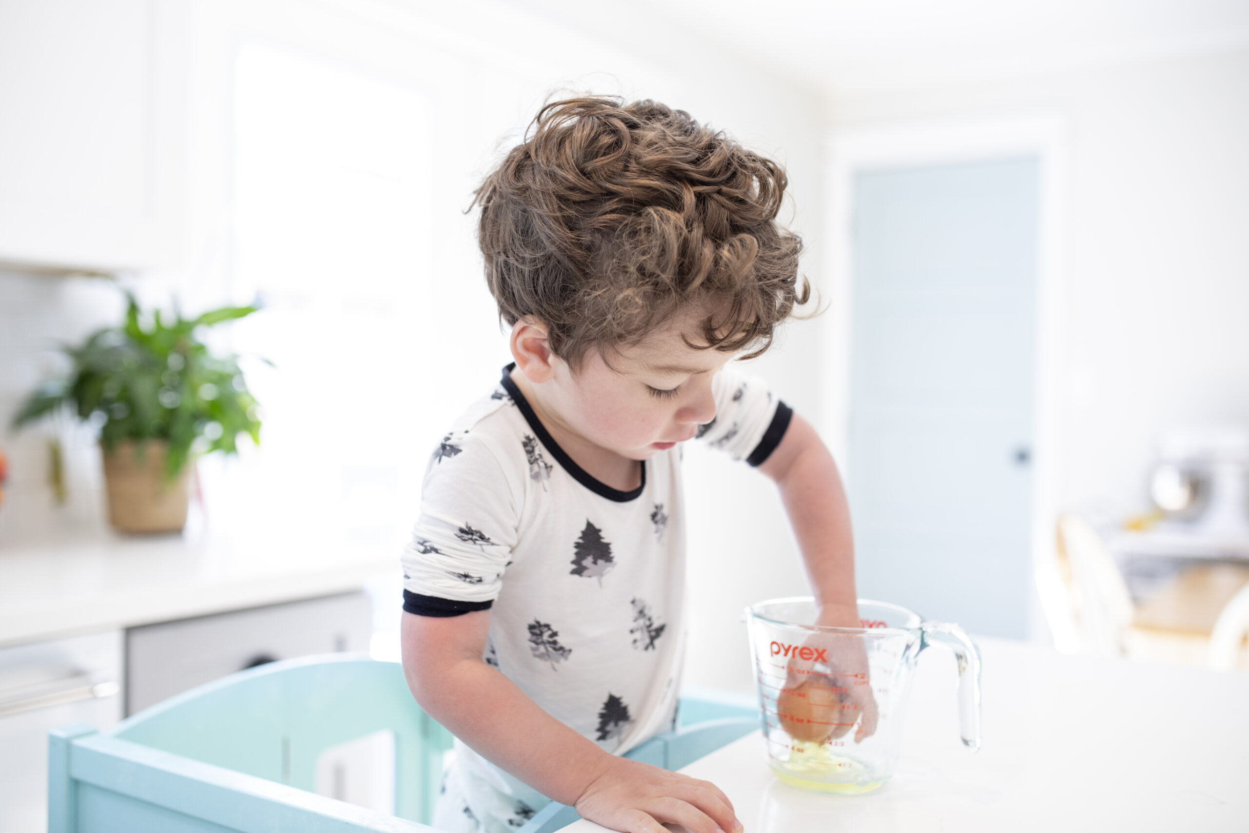 young boy cracking eggs in his kitchen