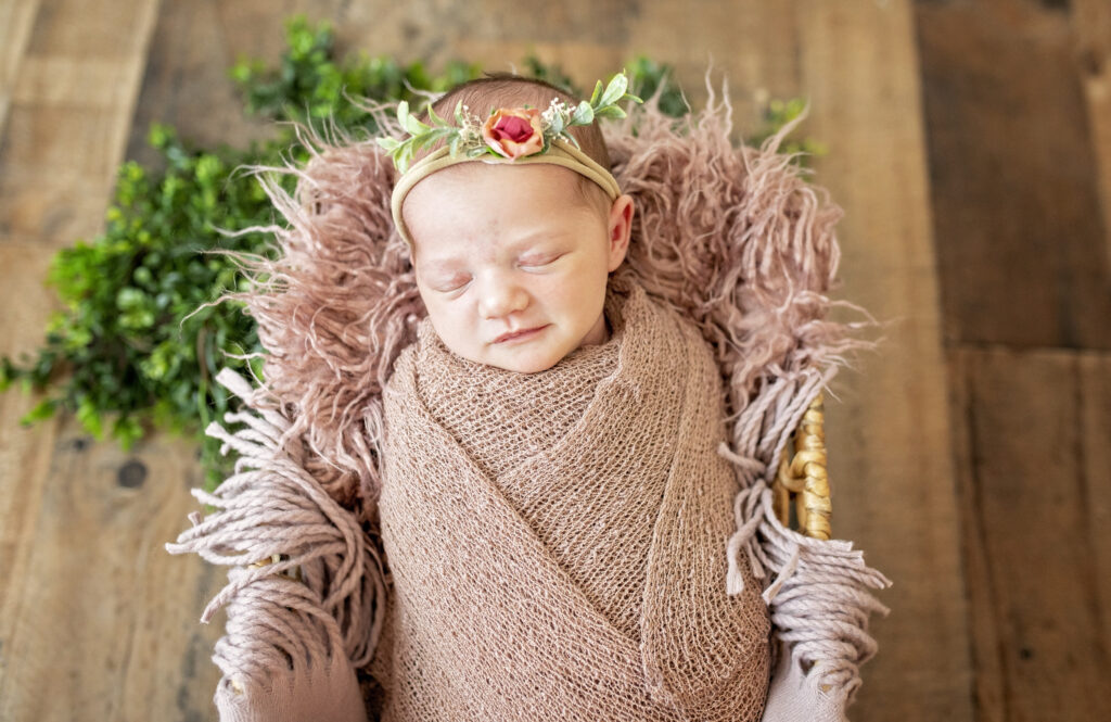 newborn girl sleeping in a basket wrapped in pink