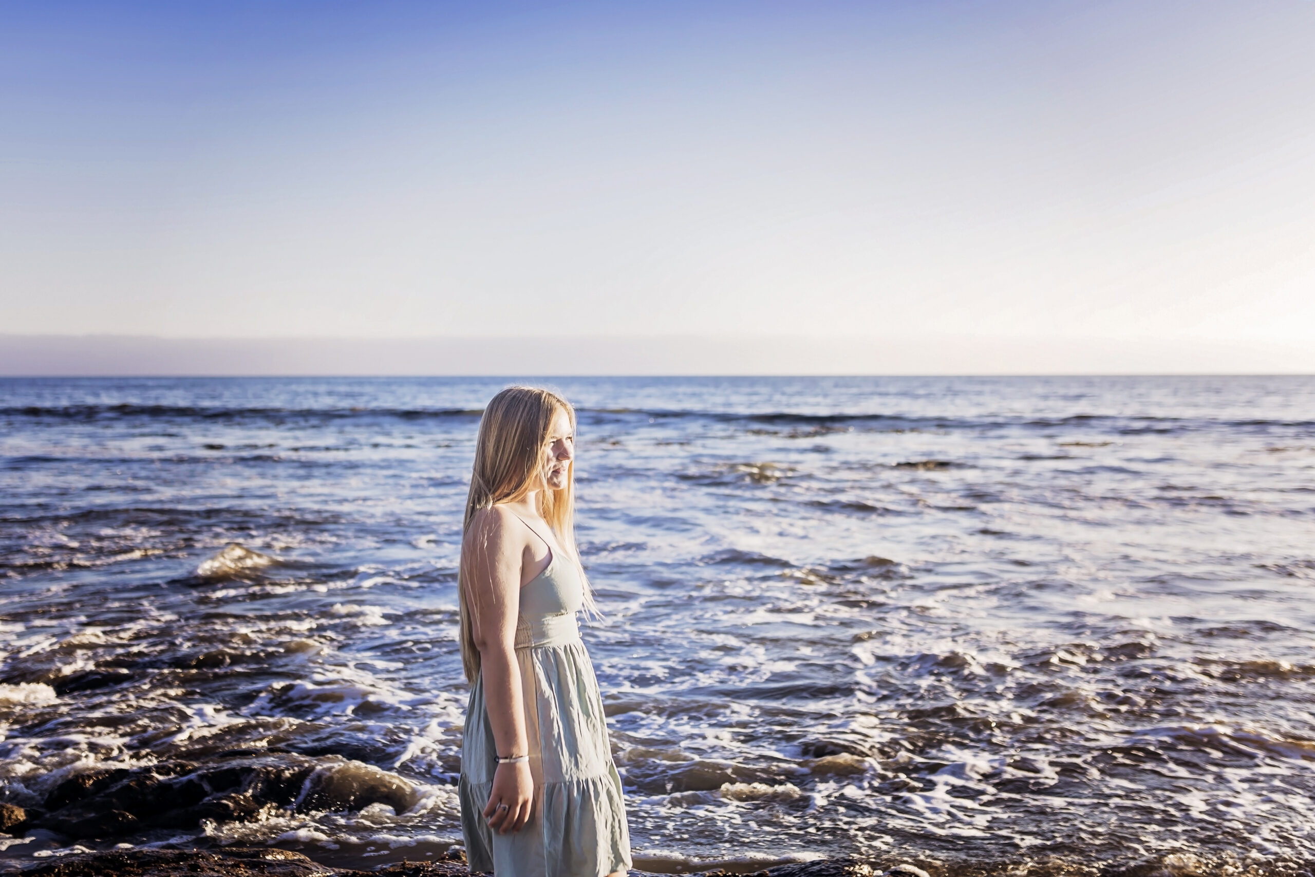 teenage girl looking off into the distance at the ocean