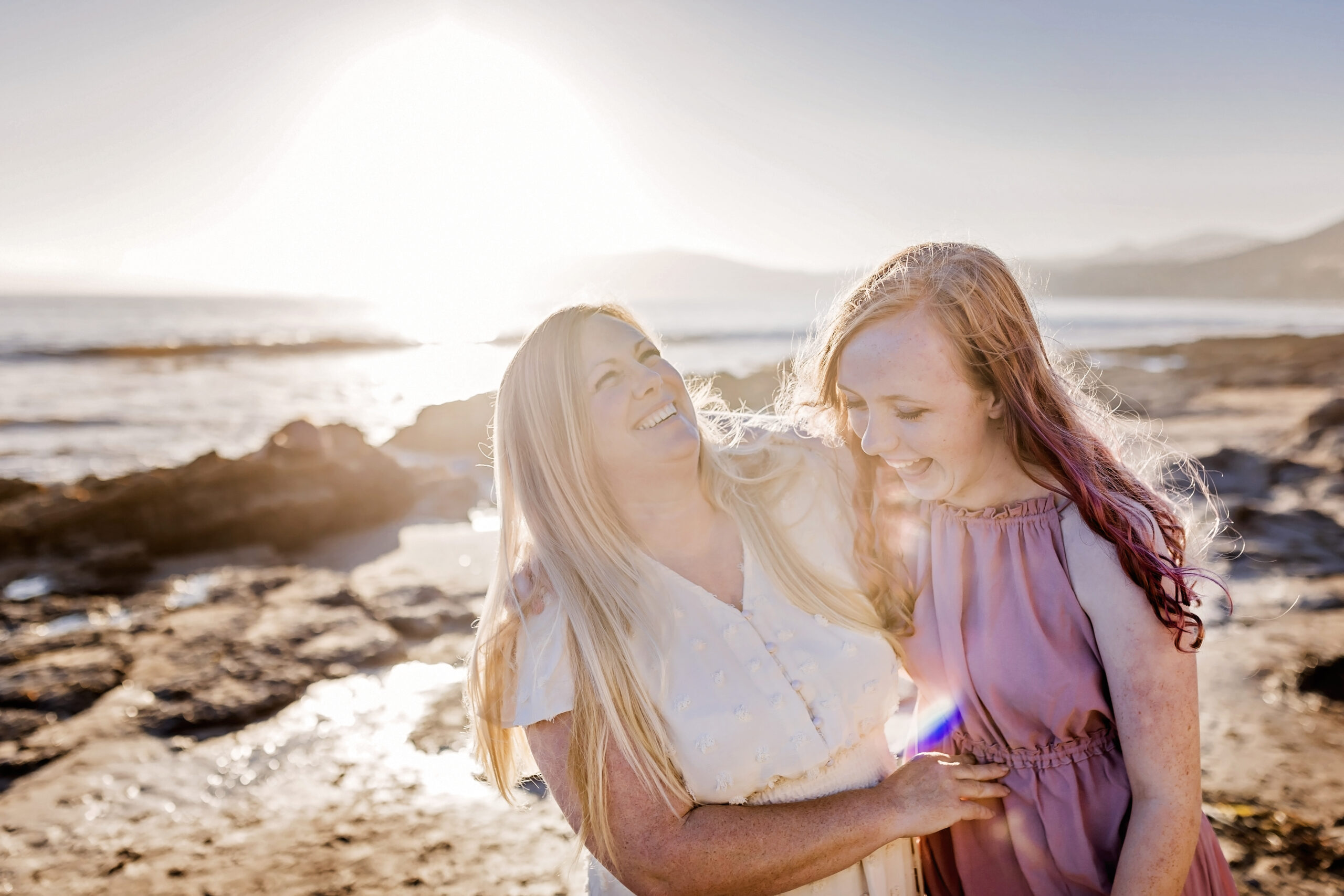 mother and daughter laugh together on the beach