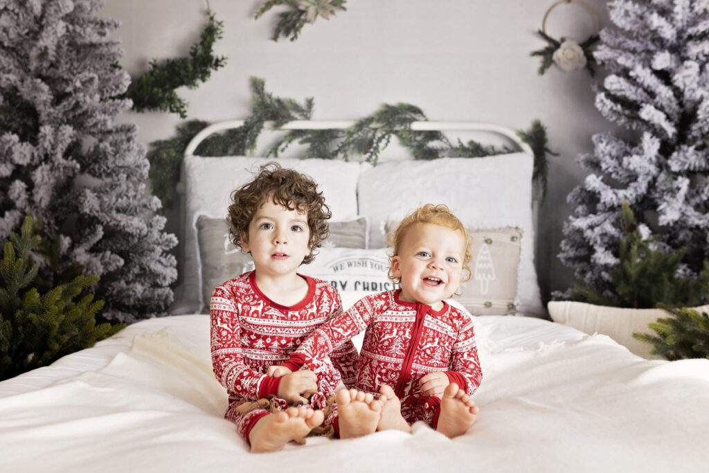 two boys in Christmas pajamas on a bed