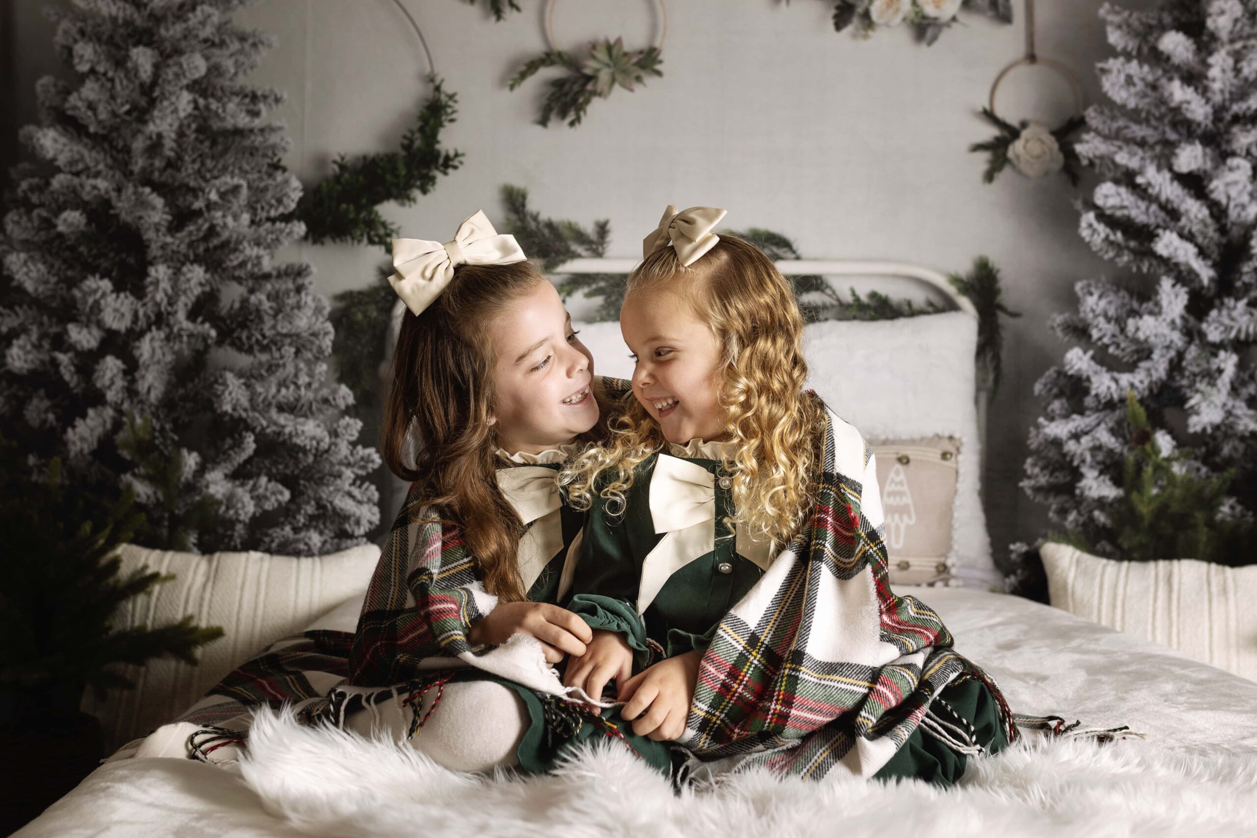 two young girls smiling at each other with a Christmas wrap around them