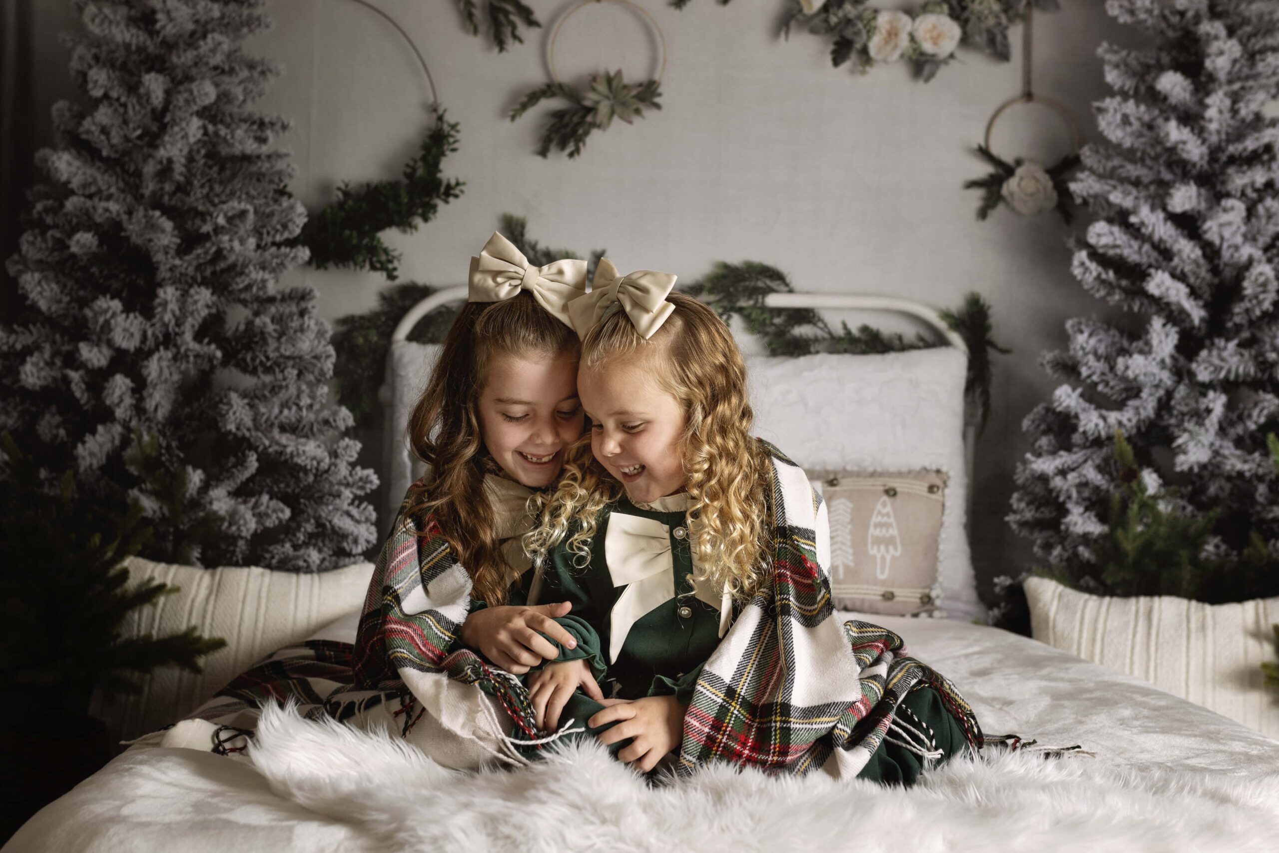 two girls laughing together on a bed in a Christmas themed set