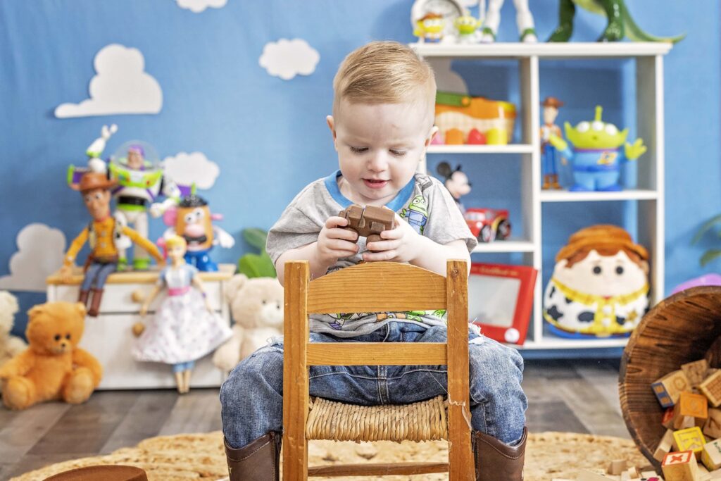 Two year old boy in a Toy Story themed set sitting on a chair