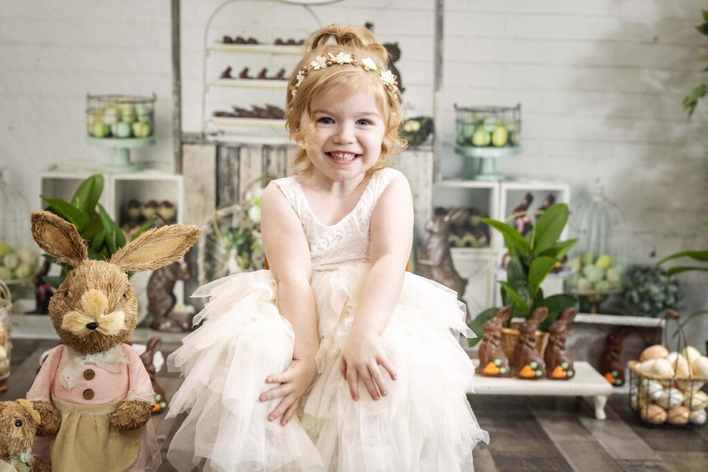 young girl in a white dress with an Easter themed backdrop