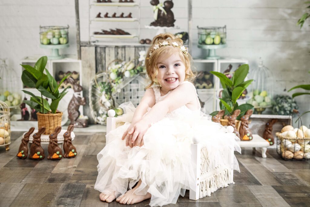 young girl in a white dress with a chocolate easter bunny themed background