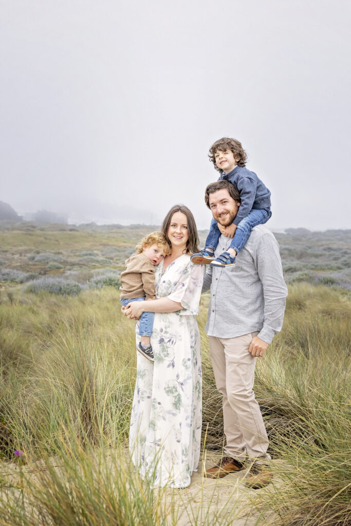 family of four posing in beach grass