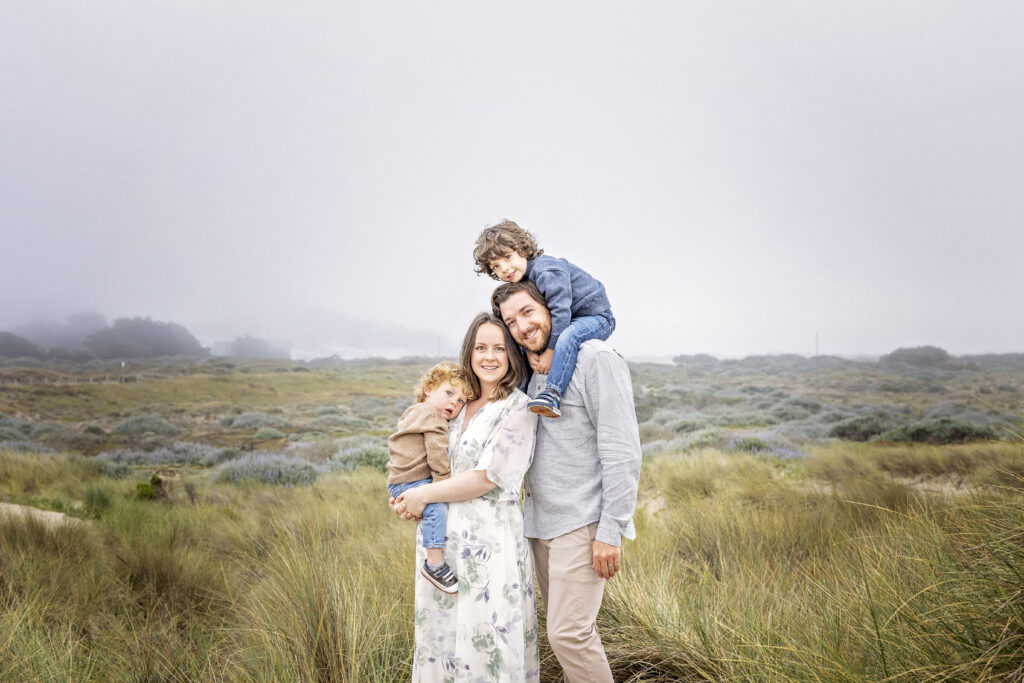 family of four standing together with long beach grass