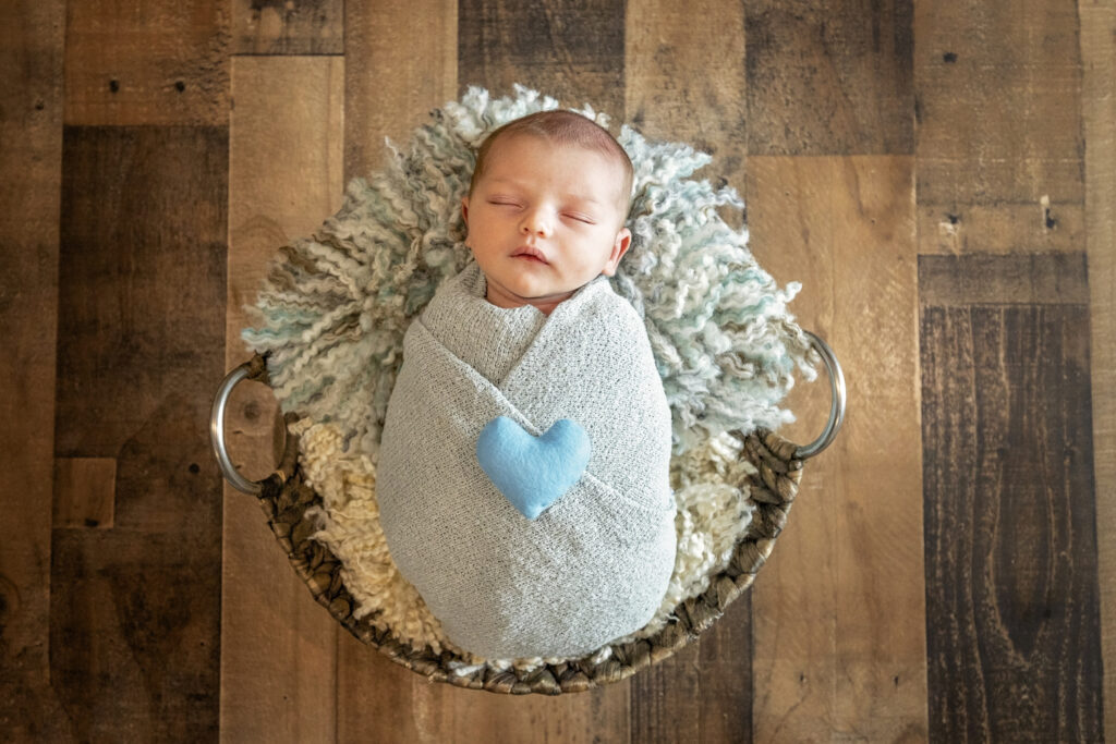 newborn boy in a light blue wrap with a blue heart on his chest