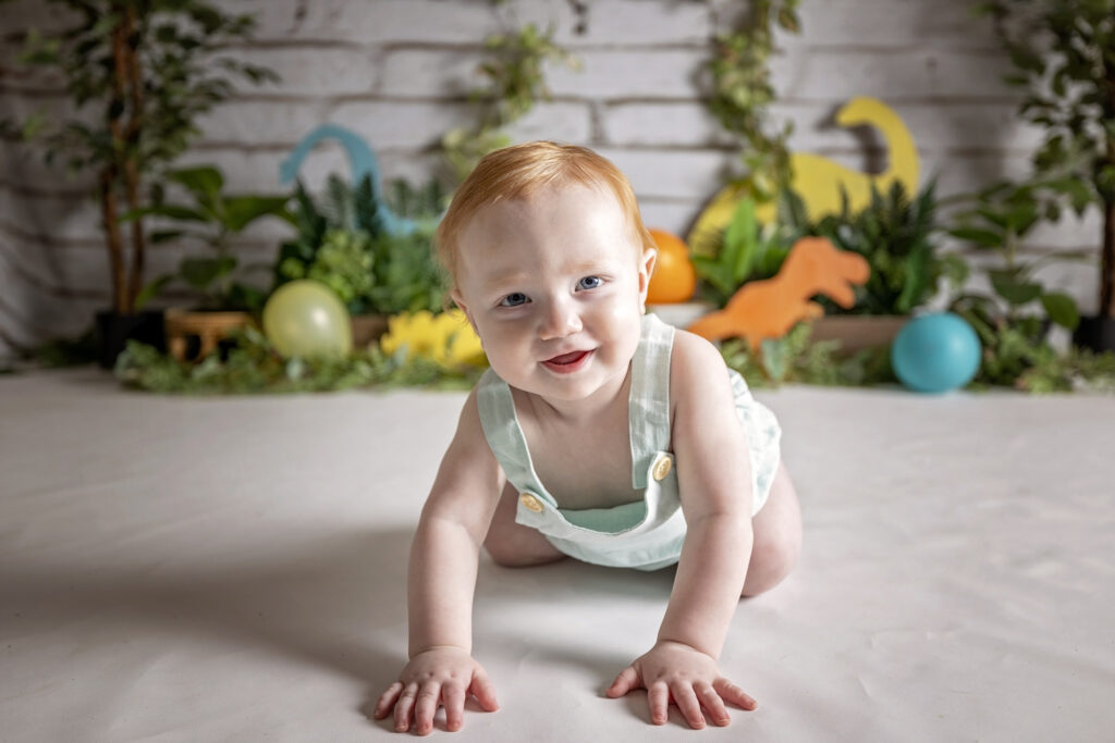 one year old boy crawling toward the camera while smiling
