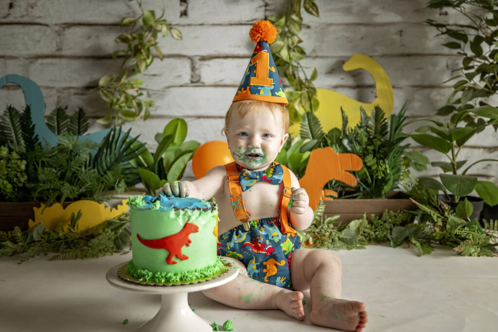 one year old boy with a dinosaur themed cake