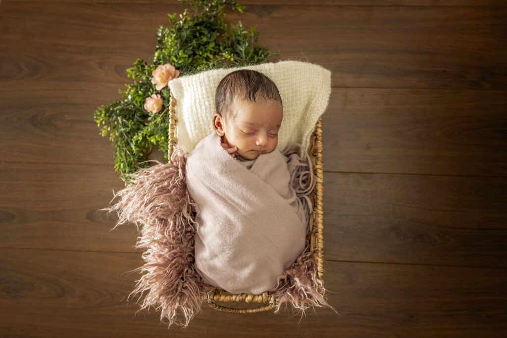 Newborn girl in a basket with pink accents
