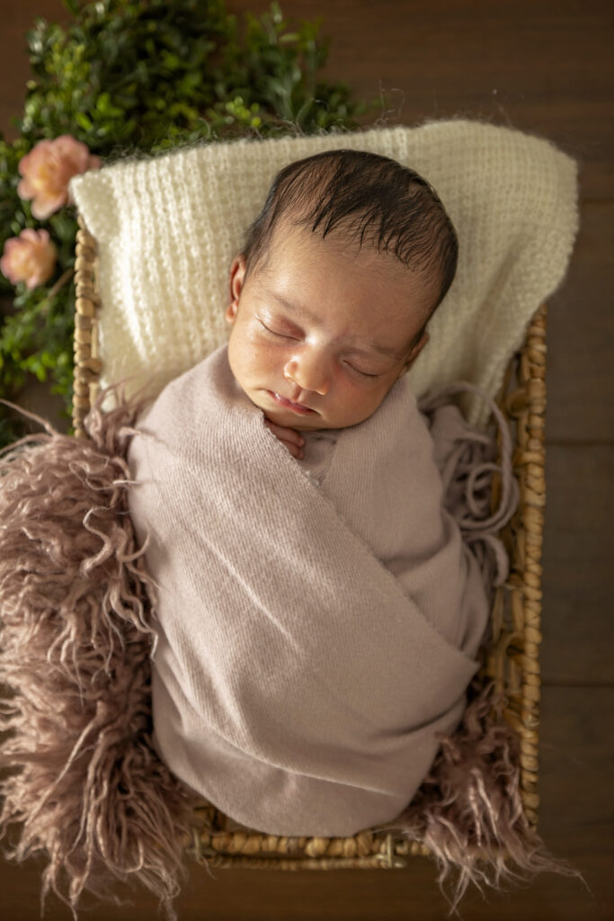 Newborn girl in a basket with pink accents