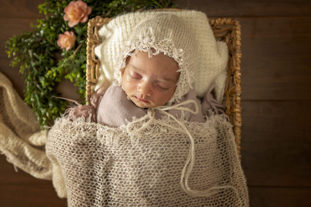 Newborn girl in a basket with a white bonnet