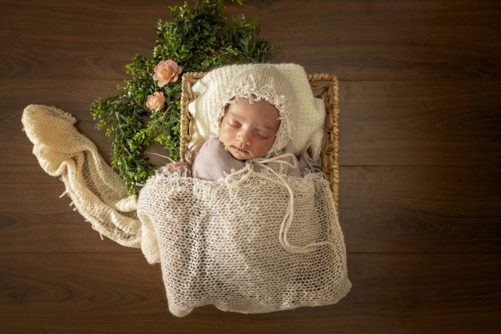 Newborn girl in a basket with a white bonnet