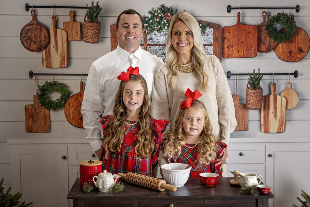 family of four standing together in a Christmas themed kitchen