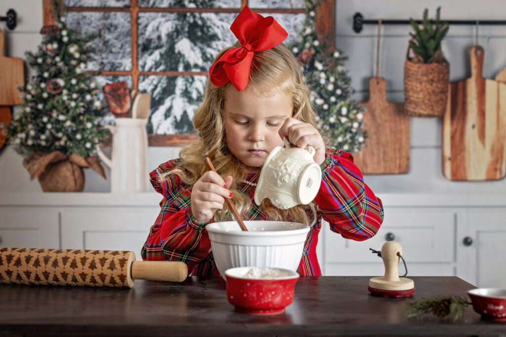 young girl pouring ingredients in a mixing bowl while in a Christmas kitchen