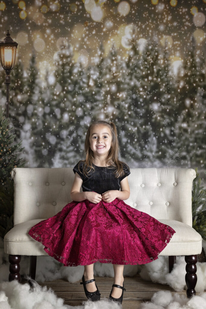 young girl in a red dress sitting on a sofa in a Christmas Tree farm