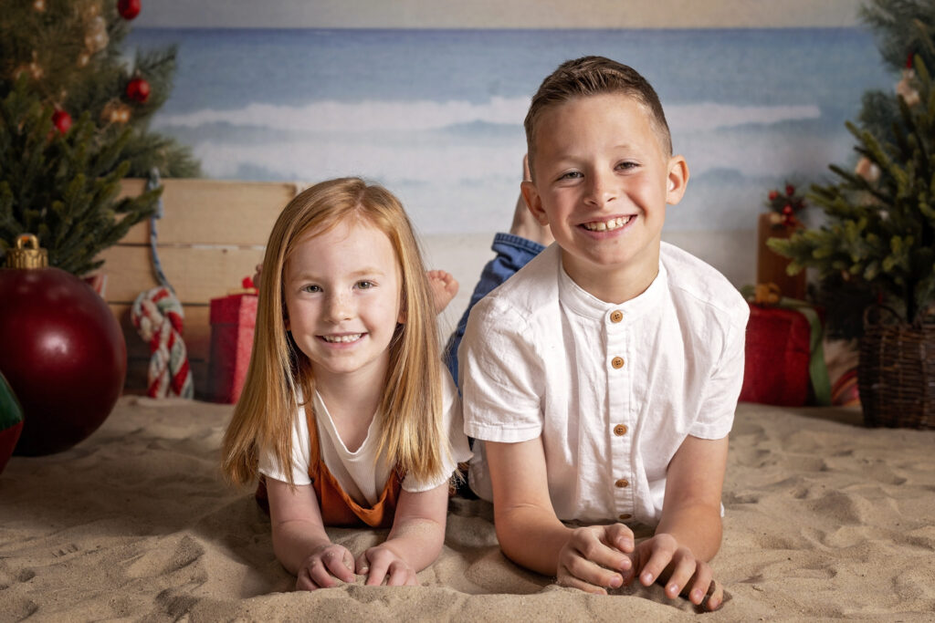 siblings looking at the camera while laying in the sand