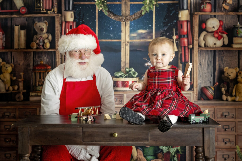 one year old girl sitting on a table with Santa Claus