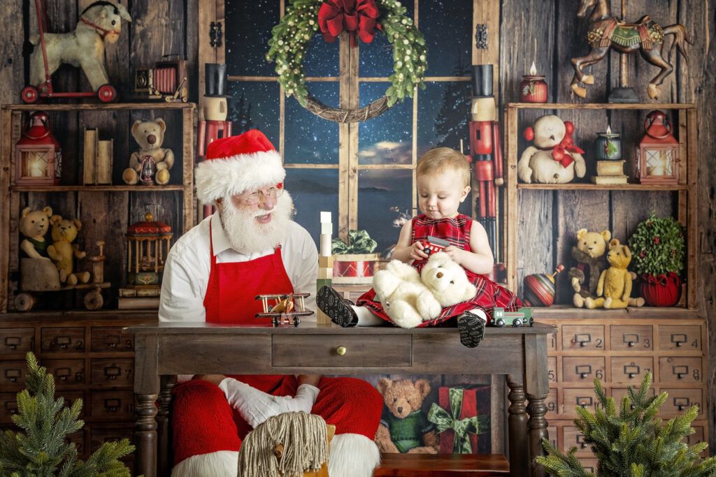 one year old girl playing with a toy train with Santa Claus