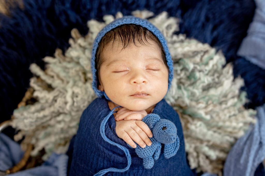 image of newborn boy in soft blue wrap, peaceful studio portrait capturing first days of life.