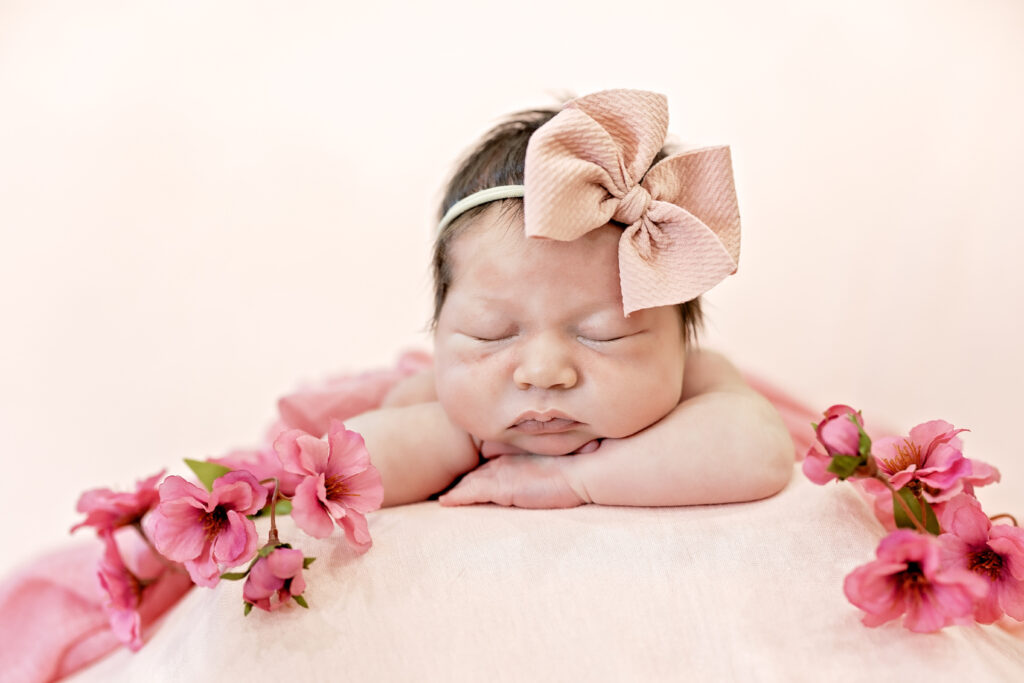 Sleeping baby girl with pink flower crown, soft studio lighting highlighting her features.