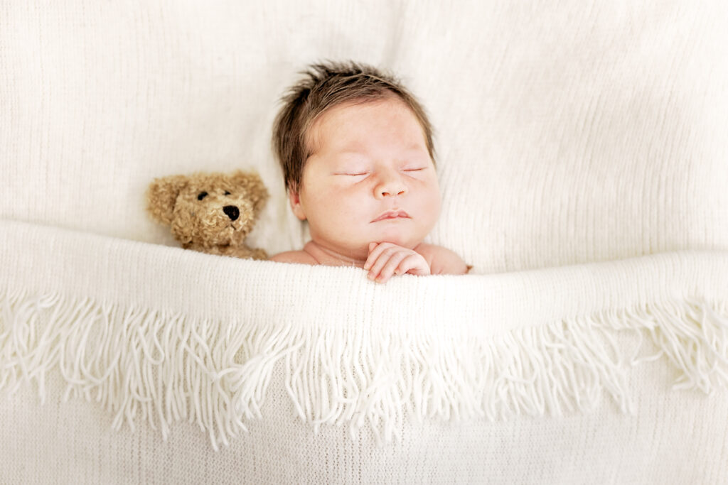 Close-up of baby’s face in cream wrap, eyes closed and peaceful.