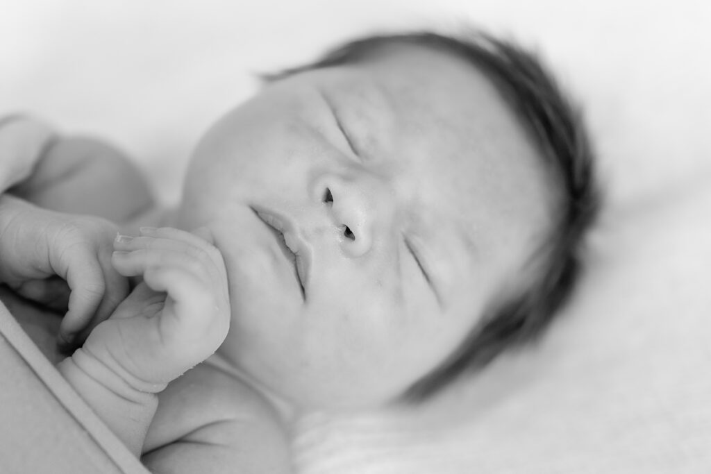 Black-and-white newborn portrait showing serene sleeping pose.