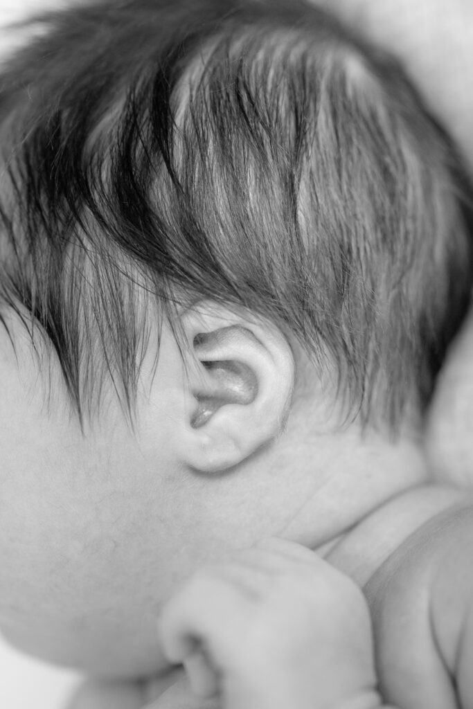Close-up black-and-white photo of newborn’s profile, soft focus on eyelashes.