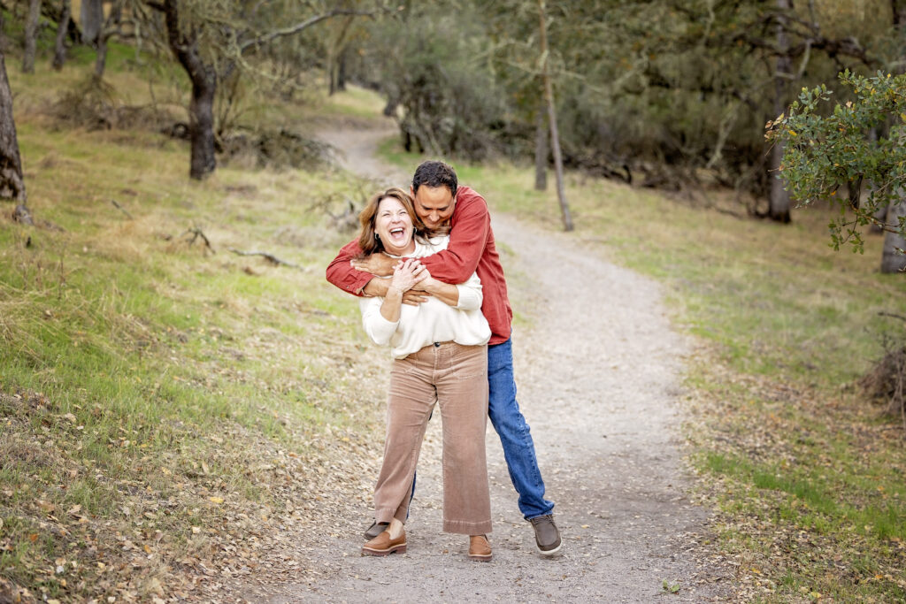 Mom and dad walking and laughing together on a wooded trail at Jim Green Trail in Atascadero
